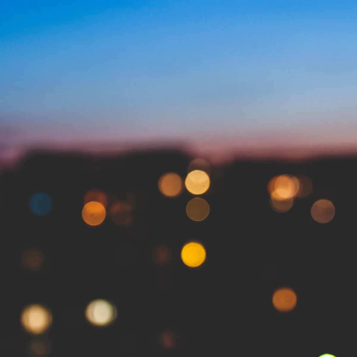 City lights thrown completely out of focus into overlapping discs of colour. Night, no subject, pure texture and glow.
