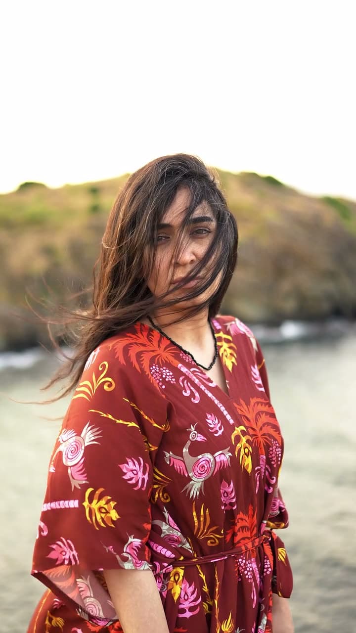 Close portrait of a woman as wind lifts her hair, she turns slowly toward the lens. Soft directional daylight, shallow depth of field, calm and intimate.